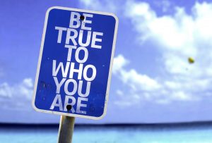 Be True To Who You Are sign with a beach on background